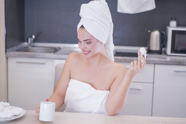 giovane ragazza seduta in cucina dopo una doccia avvolta in un asciugamano bianco e riposante
 - Foto, immagini