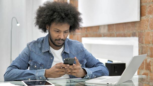 Uomo africano utilizzando Smartphone in ufficio Loft
 - Foto, immagini