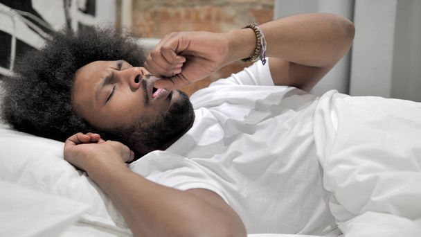 Άρρωστος Αφρικανός άνθρωπος βήχας ενώ κοιμάται στο κρεβάτι, βήχας - Φωτογραφία, εικόνα
