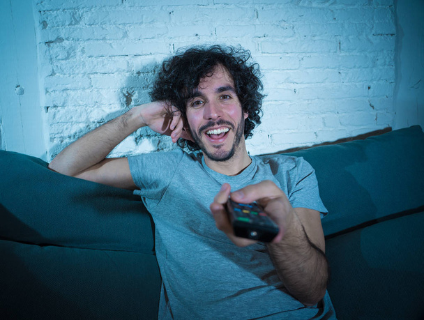 Lifestyle portrait of young man on sofa watching sports or exciting movie on television. Having fun at home enjoying streaming tv. In entertainment internet and mass media. - Фото, зображення
