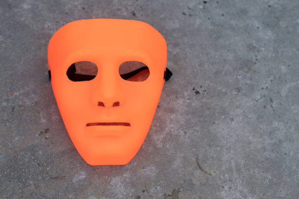 Πλήρες πρόσωπο άδεια πορτοκαλί μάσκα αλλοδαπός σε γκρι πέτρα φόντο Απόκριες - Φωτογραφία, εικόνα