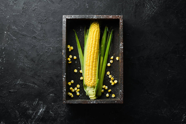 Corn in a wooden box. Vegetables. Top view. Free copy space. - Foto, imagen