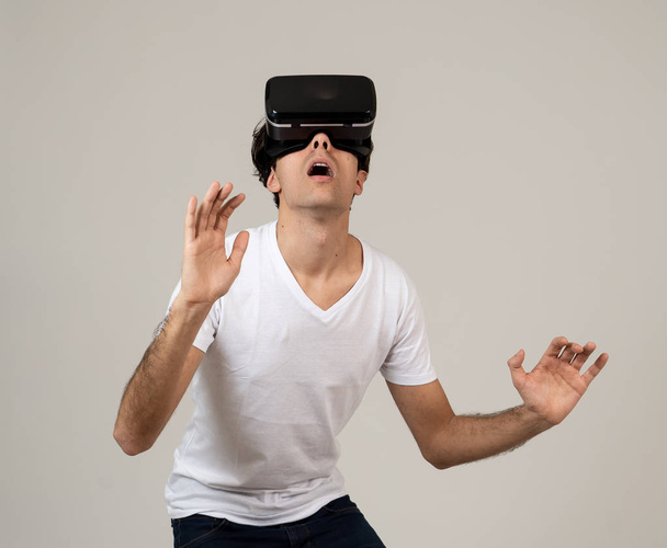 Young man using virtual reality goggles feeling excited and shock exploring virtual world making scared gestures having a scary VR adventure. Innovation New technology and Virtual Augmented Reality. - Photo, Image