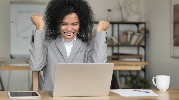 Afrikaanse zakenvrouw viert succes tijdens het werken op laptop - Foto, afbeelding