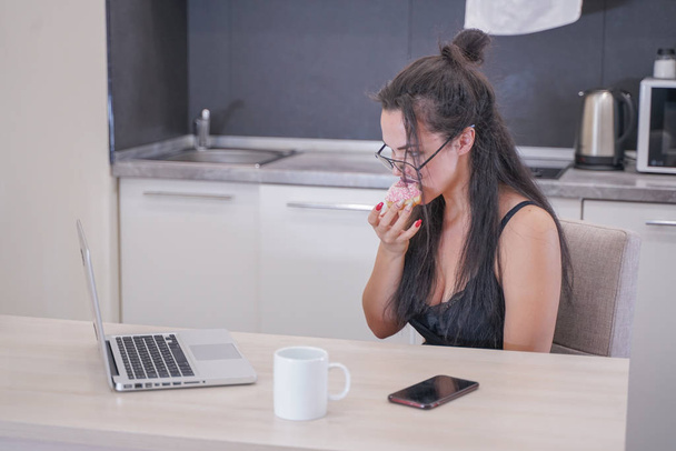 cute girl with glasses sitting at the table with a laptop at home alone - 写真・画像