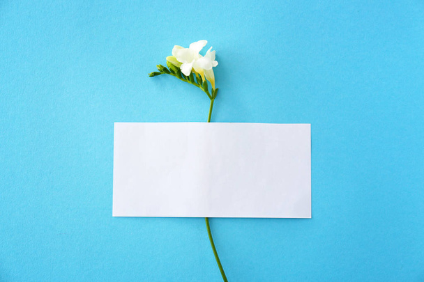 Blanco kaart en mooie Freesia bloemen op kleur achtergrond - Foto, afbeelding