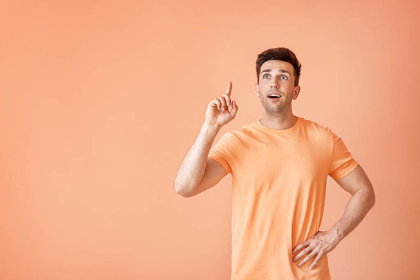Portrait of handsome man with raised index finger on color background - Photo, Image