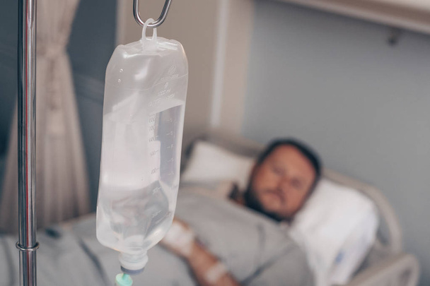 Un homme allongé sur un lit d'hôpital. Compte-gouttes dans une main d'homme dans un hôpital
. - Photo, image