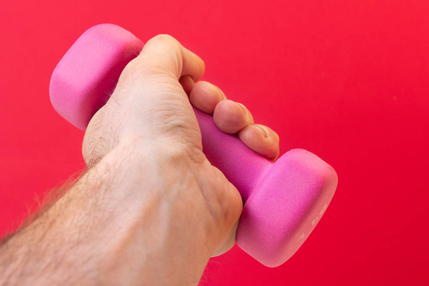 Fitness training. Dumbbell in hand on a pink background. Healthy - Fotoğraf, Görsel