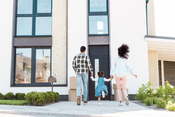 vista posteriore della coppia afro-americana con bambino che corre in una nuova casa
  - Foto, immagini