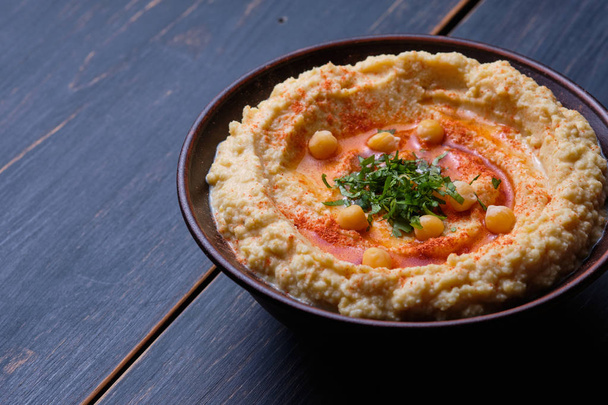 Hummus clásico con pimientos picantes en un plato de barro. Plato nacional vegetariano
 - Foto, Imagen