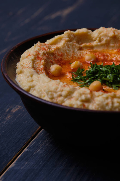 Hummus clásico con pimientos picantes en un plato de barro. Plato nacional vegetariano
 - Foto, imagen