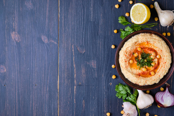 Classic hummus with hot peppers in a clay plate. National, vegetarian dish - Fotoğraf, Görsel