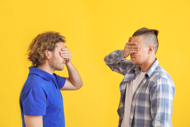 Mladí muži zakrývající oči barvou pozadí - Fotografie, Obrázek