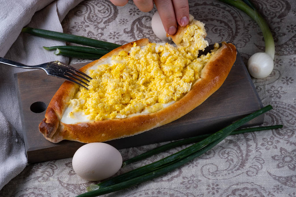 Ο άνθρωπος τρώει μισάνοιχτο κατσούρι. Γέμιση από τυρί, αυγά και βούτυρο. Κέικ φούρνου σερβιριστούν για φαγητό. Γεωργιανή κουζίνα. - Φωτογραφία, εικόνα