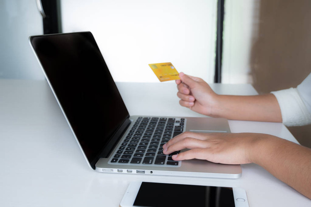 Frau nutzt Kreditkarte für Online-Einkäufe auf Laptop und Handy - Foto, Bild