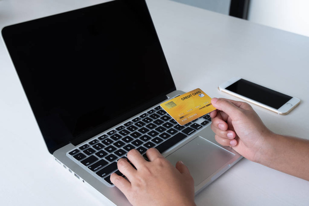 Frau nutzt Kreditkarte für Online-Einkäufe auf Laptop und Handy - Foto, Bild