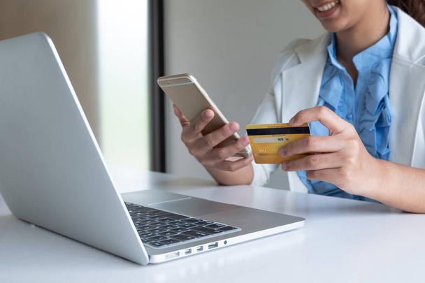 donna utilizzare la carta di credito per lo shopping online sul suo computer portatile e telefono
 - Foto, immagini