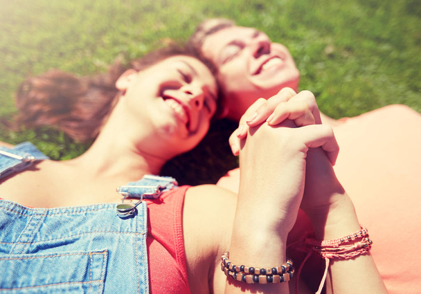 happy teenage couple lying on grass at summer - Zdjęcie, obraz