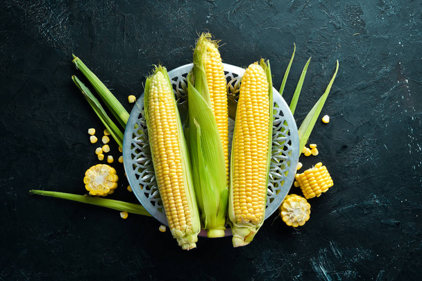 Fresh corn on a black background. Vegetables. Top view. Free copy space. - Zdjęcie, obraz