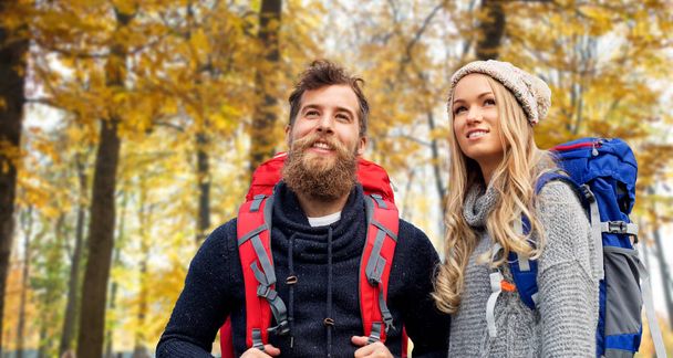 smiling couple with backpacks hiking in autumn - Valokuva, kuva