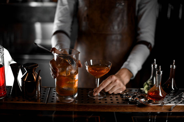 Bartender pouring alcohol cocktail with the strainer - 写真・画像