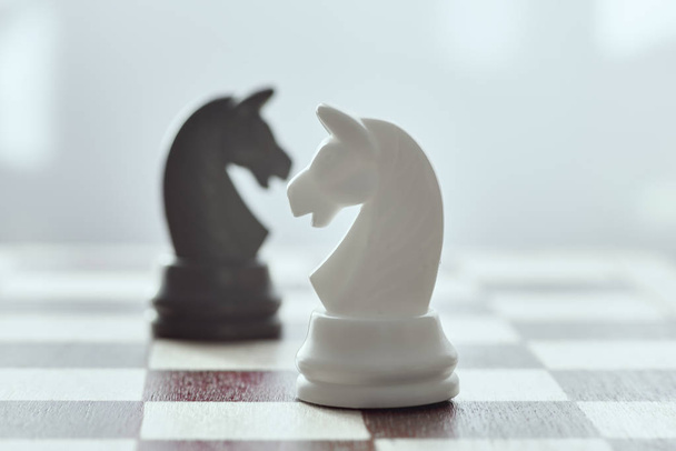 White horse on a black horse in a blur, two on the chessboard. Chess is an strategy and intelligence board game. - Photo, Image