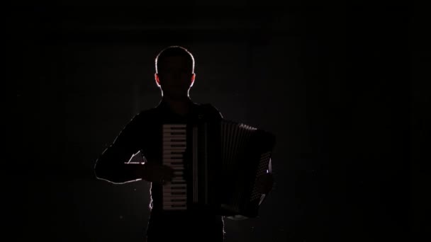 joven acordeonista toca el acordeón magistralmente en el estudio sobre un fondo negro, aislado
 - Metraje, vídeo