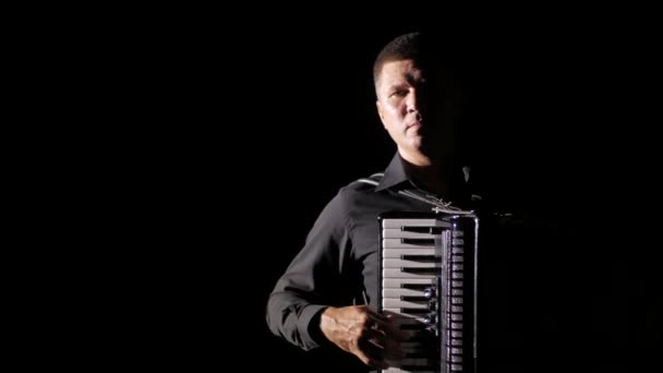 mladý hudebník virtuos hraje na harmoniku mistrovsky ve studiu na černém pozadí, izolované, close-up  - Záběry, video