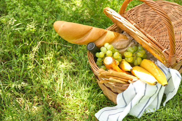 Плетений кошик зі смачною їжею та напоєм для романтичного пікніка в парку
 - Фото, зображення