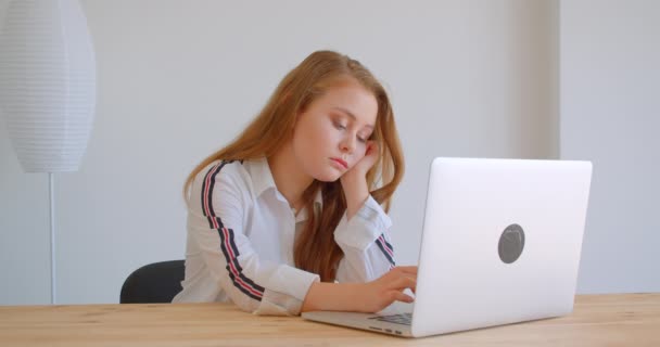 Closeup portrét mladé bělošské dívky, která používá latop a nudí se uvnitř bytu - Záběry, video