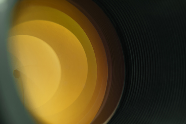 Piękny obiektyw aparatu z żółtym światłem szkła na czarnym tle. - Zdjęcie, obraz