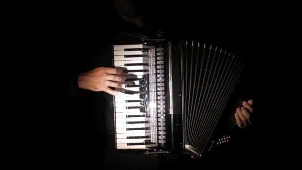 hombre músico magistral toca el acordeón en el estudio sobre un fondo negro, primer plano de las manos y las llaves, aislado
 - Metraje, vídeo