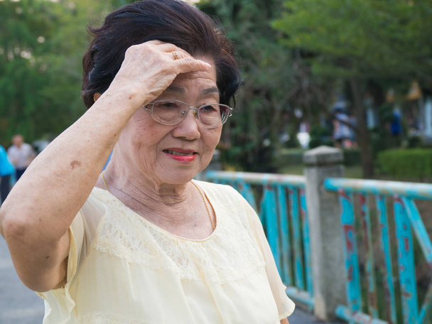 La anciana asiática llevaba gafas. ella no se sentía cómoda con dolores de cabeza.Cuando la mujer mayor caminando en el parque
 - Foto, imagen