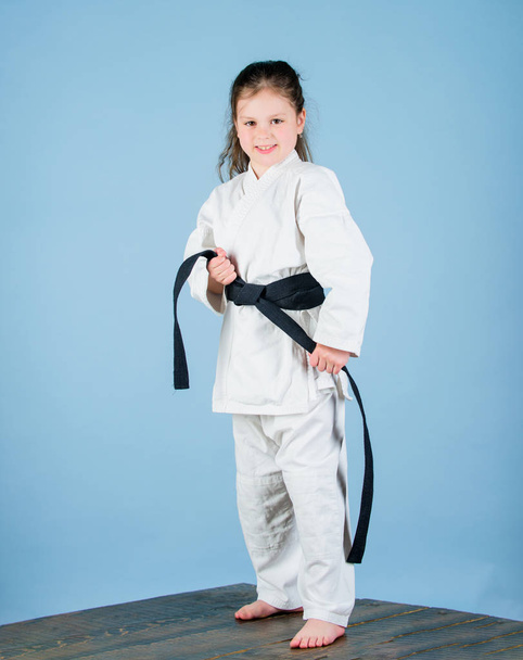Activity and sport. Karate gives feeling of confidence. Strong and confident kid. Girl little child in white kimono with belt. Karate fighter ready to fight. Karate sport concept. Self defence skills - Fotoğraf, Görsel