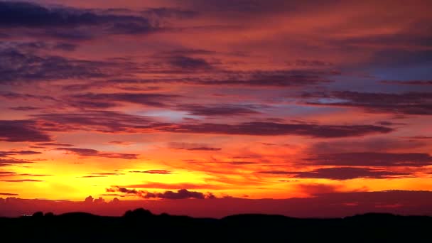 zonsondergang oranje gele hemel en donker rode wolk bewegen op vervagen silhouet berg - Video