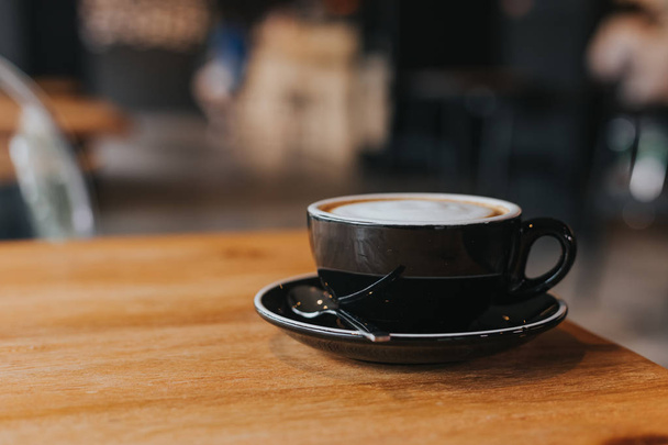 hot coffee in black cup on wooden table. - Foto, Imagen