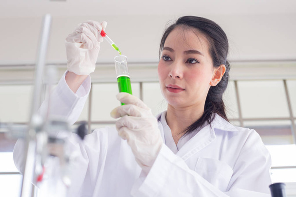 vrouwen wetenschapper in laboratoriumchemicaliën groen monster uit een test - Foto, afbeelding