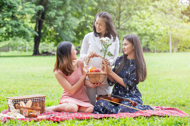 Aziatische familie moeder en tiener dochter gelukkig picknick met fruit ba - Foto, afbeelding