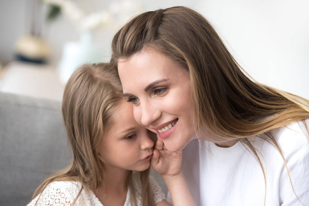 Daughter whispering to moms ear a secret - Фото, изображение