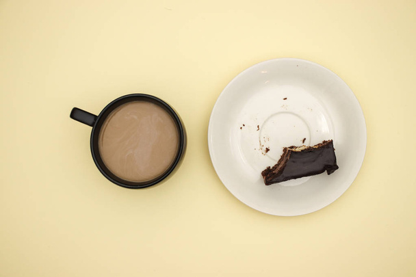 Cup of coffee and chocolate cake on yellow background  - Fotó, kép