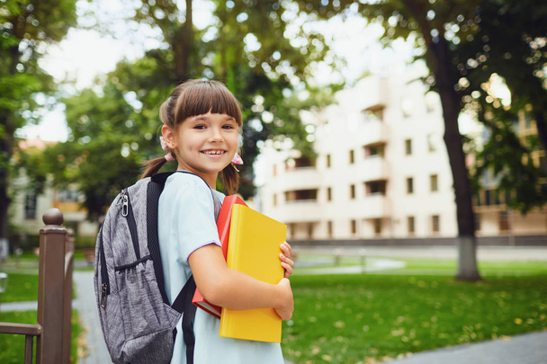 Happy little student girl with a backpack on her way to school. - 写真・画像