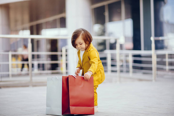 Cute little girl with shopping bag in a city - Фото, изображение