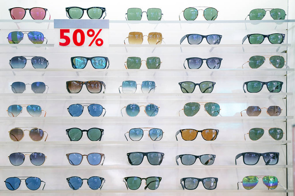Fique com óculos de sol. Óculos de sol, um desconto de 50% display backlight stand na prateleira não identificada no shopping
. - Foto, Imagem