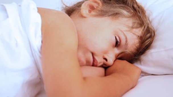 Little girl openes her eyes and awake on pillow - Filmati, video