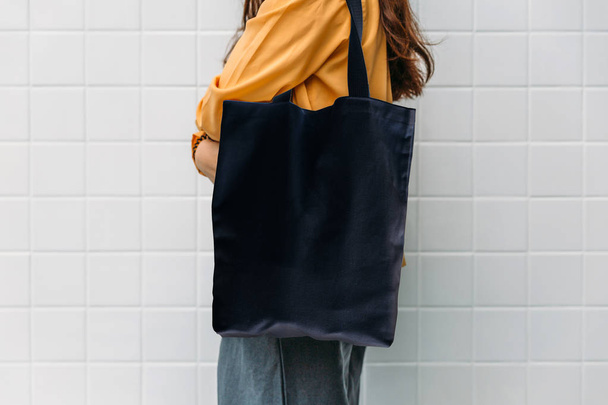Woman is holding black bag canvas fabric for mockup blank template. - Fotó, kép