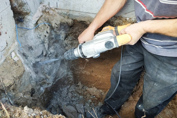 Operaio edile utilizzando trapano pneumatico martello per tagliare il mattone di cemento muro, primo piano
 - Foto, immagini