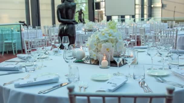 Καταπληκτική σκηνή έτοιμη για μια γαμήλια γιορτή. Στρογγυλά τραπέζια είναι όλα διακοσμημένα σε λευκό με όμορφα και φανταχτερά λευκά μπουκέτα. - Πλάνα, βίντεο