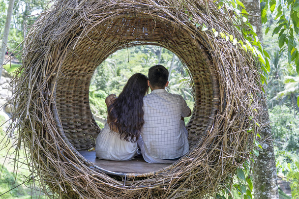 Asian woman and man enjoying his time sitting on a bird nest in the tropical jungle near the rice terraces in island Bali, Indonesia - Foto, Imagen