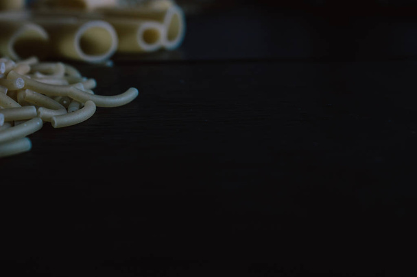 Herkullinen vastavalmistettua raakaa pastaa valmis keitettäväksi. Tuore pasta musta liuskekivi tausta
. - Valokuva, kuva